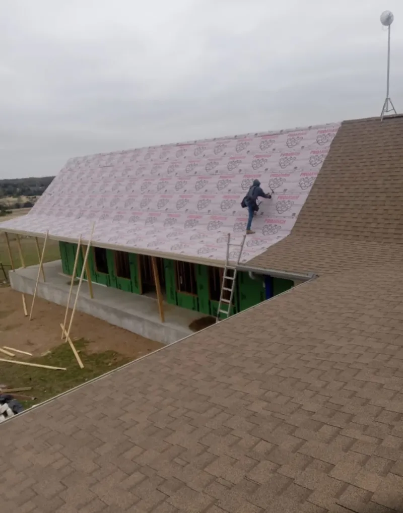 Worker preparing underlayment for a metal roof installation in Brownfield